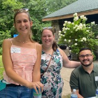 3 GVSU Alumni smiled together towards camera near a picnic table at John Ball Zoo